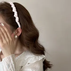 Close-up of a stylish pink and white plaid fabric headband worn on an elegant hairstyle