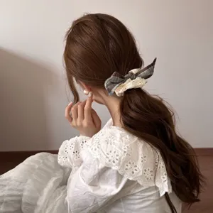 Achteraanzicht van een model met een stijlvolle scrunchie van ruitjesstof en wit kant in haar
