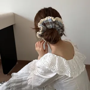 Gedetailleerde weergave van een geruite scrunchie met kantafwerking in een knot