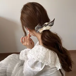 Detailopname van een geruite kant scrunchie gedragen in een elegante paardenstaart
