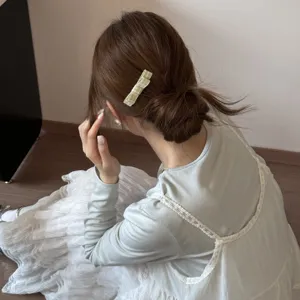 Detail view of a Korean style green gingham bow hair clip worn on a low bun hairstyle