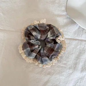 Gedetailleerde weergave van een dubbellaagse geruite scrunchie met crème kantafwerking