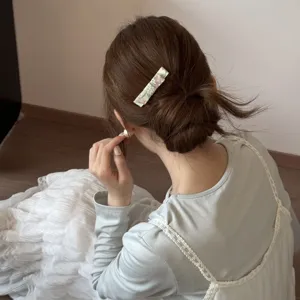 Close-up of a vintage rectangular floral hair clip styled on a low bun hairstyle for women