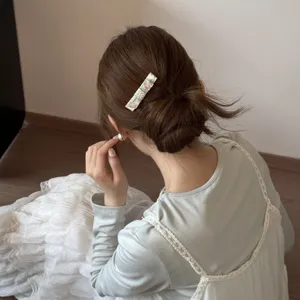 Close-up view of a floral rectangular hair clip styling a messy bun on brown hair