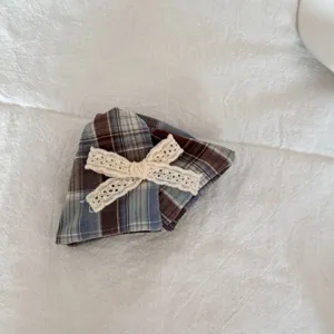 Detailopname van geruite scrunchie met beige kanten strik op witte stof
