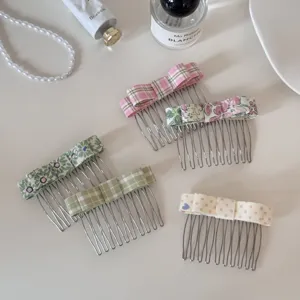 Detailed view of assorted floral and plaid bow hair combs on a soft cream base