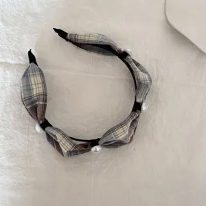 Detail van vintage geruite stoffen haarband versierd met elegante parels op witte achtergrond