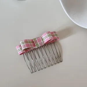 Detail view of a stylish pink checkered bow hair comb accessory for elegant hairstyles
