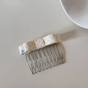 Detailed close-up of a Korean-style polka dot bow hair comb for styling bangs and fringe
