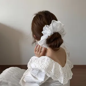 Weißer Haargummi aus Organza auf einem Dutt, eleganter Haarschmuck im koreanischen Stil.