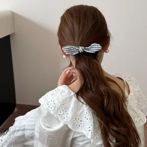 Coletero con lazo de cuadros vichy en coleta baja, combinado con un vestido de encaje blanco.