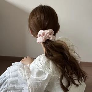 Détail d'un chouchou nuage rose à pois porté sur une coiffure en queue de cheval.