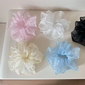 Set aus fünf Organza-Haargummis mit Perlen in verschiedenen Farben auf weißer Fläche.