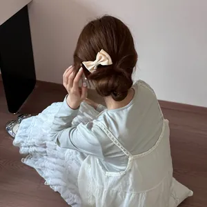 Elegant cream bow hair comb for women in Korean style, detail shot on bun hairstyle