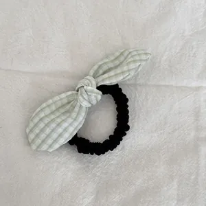 Detalle de un coletero con lazo de cuadros verde y blanco y base de goma negra.