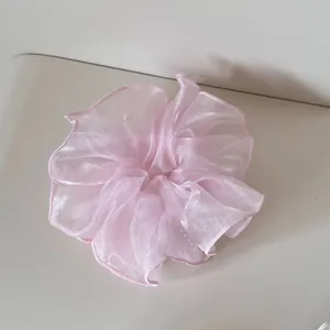 Detailansicht eines zartrosa Organza-Haargummis mit eleganten, gerafften Kanten