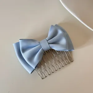 Detail view of a light blue satin double bow hair comb accessory with silver metal teeth