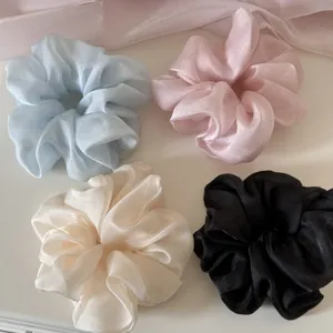 Detailed macro view of soft mesh scrunchies in pastel blue, pink, cream, and black colors.