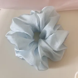 Detailed close-up showing the soft texture of a light blue shimmering mesh scrunchie