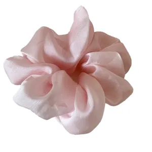 Elegant pink organza scrunchie hair tie with soft pleated texture on white background