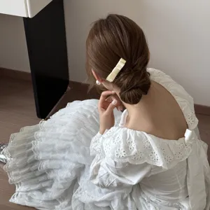 Detailed macro view of a sweet cream bow hair comb on a low bun hairstyle, ballet style.