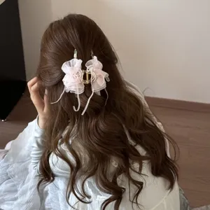 Detailed view of an elegant pink mesh bow hair claw clip on long wavy brown hair