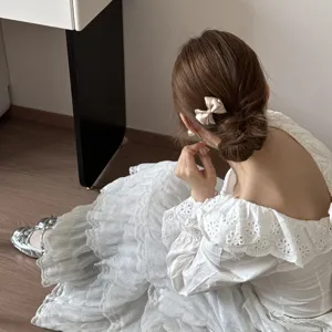 Elegante pinza para el pelo con lazo de seda en una modelo con vestido de encaje blanco suave