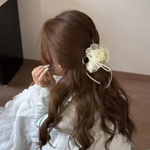 Close-up detail of elegant cream mesh bubble hair claw clip styled on long wavy brown hair.