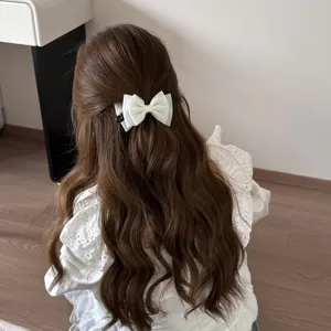 Elegant white fabric bow hair clip comb accessory in brown wavy hair for styling