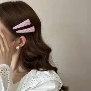 Detail view of sweet purple striped hair clips with cherry charms worn on wavy brown hair