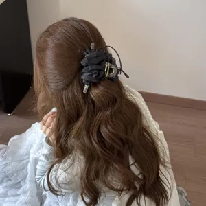 Detailed view of the black mesh ruffled hair claw clip on long wavy brown hair