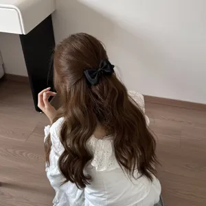 Back view of a sweet black bow hair clip elegantly styled on long wavy brown hair