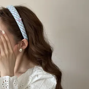 Close-up detail of the blue and purple plaid headband worn on head with cherry charm