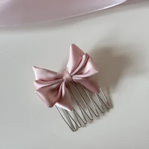 Toma detallada de un dulce peine para el cabello con lazo de satén rosa para niñas
