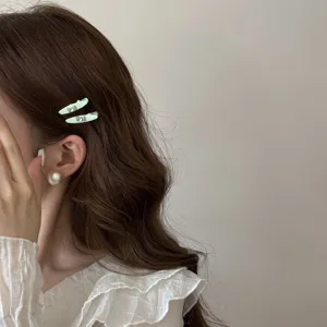 Close-up of sweet light green duckbill hair clips with rhinestones on model's hair