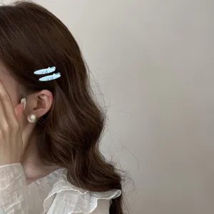 Detail showing light blue bow hair clips with rhinestones on brown wavy hair.