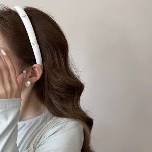 Primer plano de una diadema acolchada blanca con pequeños lazos rosas dulces