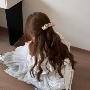 Détail d'une barrette à fleurs vintage sur de beaux cheveux bruns ondulés