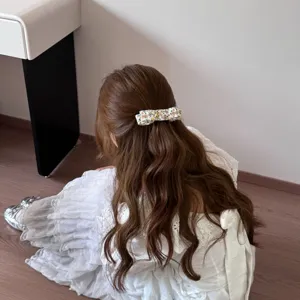 Barrette à cheveux en tissu fleuri portée dans une coiffure demi-attachée élégante