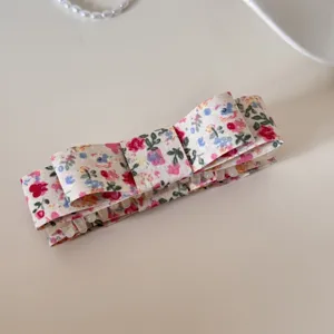 Détail d'une pince à cheveux en tissu avec un motif floral de style vintage.