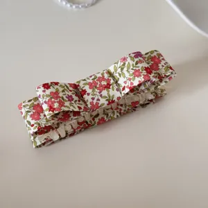Vue détaillée d'une barrette à ressort en tissu à fleurs avec motifs floraux rouges.
