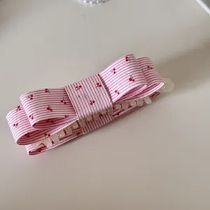Vue détaillée d'une pince à cheveux en tissu rayé rose avec motifs de cerises pour filles