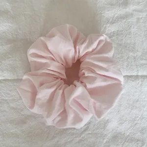 Vue détaillée d'un chouchou rose doux et duveteux sur un tissu blanc texturé
