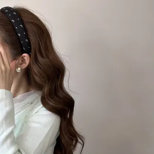Gros plan d'un serre-tête en satin noir de style coréen avec des motifs de nœuds blancs