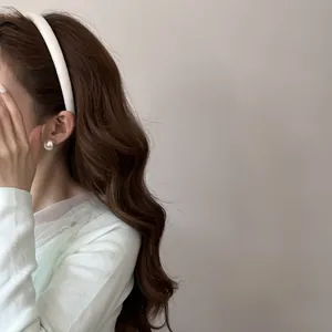 Détail d'un serre-tête en satin blanc sur cheveux bruns ondulés pour un look élégant