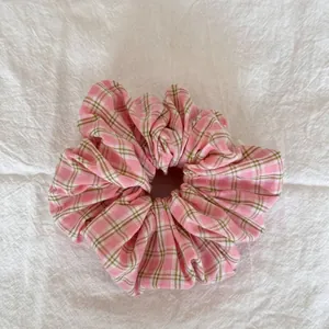 Détail d'un chouchou à carreaux roses montrant la texture douce du tissu