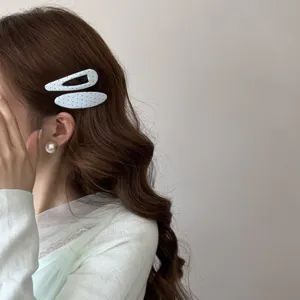 Gros plan de barrettes à cheveux en tissu blanc à pois sur des cheveux bruns ondulés