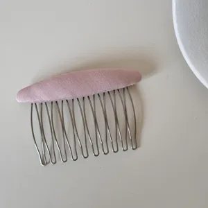 Dettaglio di un pettine per capelli in tessuto rosa con denti metallici lisci per donne.