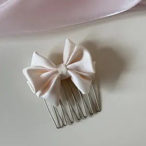Detalle de un elegante peine para el cabello con lazo de satén crema para peinar el flequillo