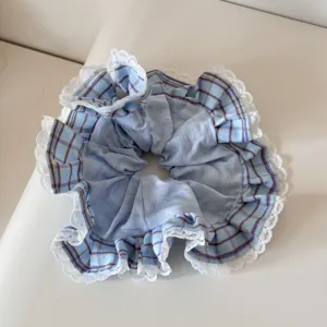 Macro detail of a blue and purple plaid scrunchie hair tie with delicate white lace trim.